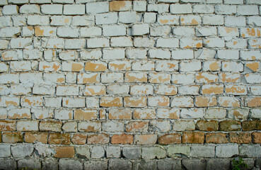 Background of old vintage dirty brick wall with peeling plaster, texture. Peeling paint on beige bricks