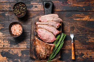 Sliced Roast beef sirloin tri tip steak bbq. Dark wooden background. Top view