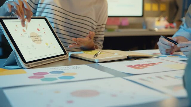 Asia businesspeople meeting plan analysis statistics brainstorm and header of team hold tablet point graph chart and employee take note in modern home office night. Finance strategy success concept.