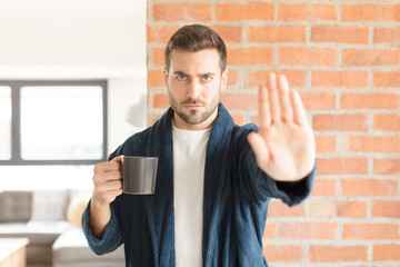 handsome man looking serious, stern, displeased and angry showing open palm making stop gesture