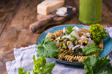 Cime di rapa pasta in a plate on with parmesan on a wooden table. Traditional food of the south of Italy, from Puglia. Rustic style photo. 
