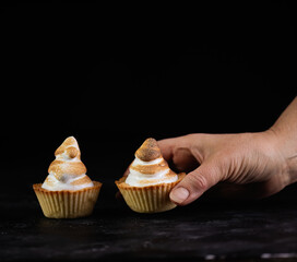Hand taking traditional french lemon tart on dark backgound