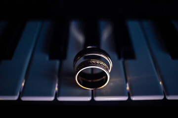 Two wedding rings on a piano with dark background