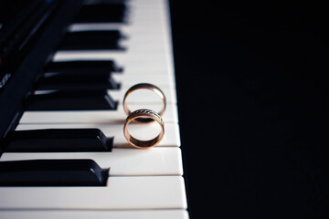 Two wedding rings on a piano with dark background
