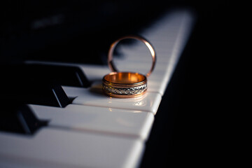 Two wedding rings on a piano with dark background
