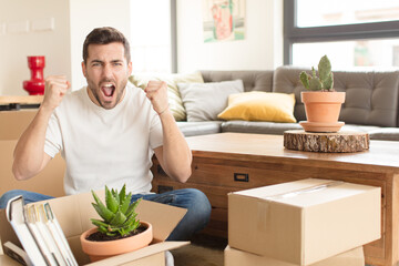 handsome man shouting aggressively with an angry expression or with fists clenched celebrating...