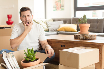 handsome man with mouth and eyes wide open and hand on chin, feeling unpleasantly shocked, saying...