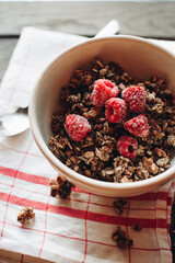 Delicious and healthy breakfast with raspberries. Morning aesthetics and beautiful layout on a wooden table. Granola for healthy breakfast.
