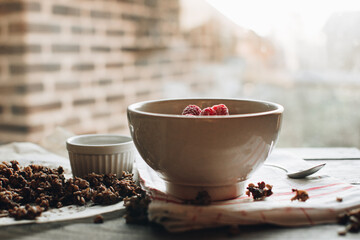 Delicious and healthy breakfast with raspberries. Morning aesthetics and beautiful layout on a wooden table. Granola for healthy breakfast.