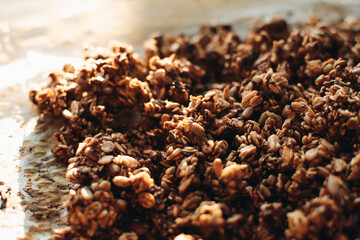 Homemade granola with nuts and seeds on baking sheet with ingredients. Granola for healthy breakfast.