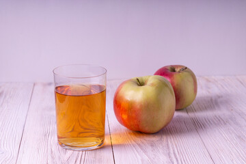 Apple juice in a glass. Against the background of white wooden boards.