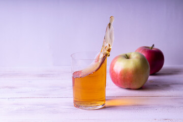 Splash of apple juice in a glass. Against the background of white wooden boards.