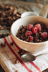 Delicious and healthy breakfast with raspberries. Morning aesthetics and beautiful layout on a wooden table. Granola for healthy breakfast.