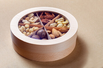 wooden round gift box with a set of different types of nuts for a healthy diet of vegetarians on paper eco craft background, nobody.
