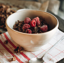 Delicious and healthy breakfast with raspberries. Morning aesthetics and beautiful layout on a wooden table. Granola for healthy breakfast.