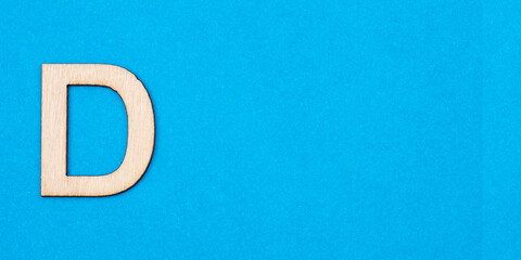 Letter D in wood on blue background