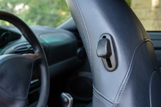Sports car drivers seat tilts forward with the flip of a lever located on the headrest.