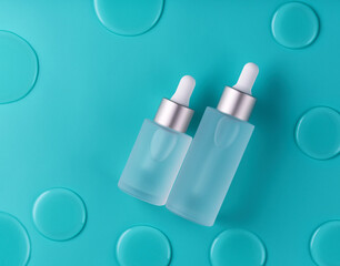 Natural cosmetics, serum for hair and skin care with water drops on a blue background, top view.