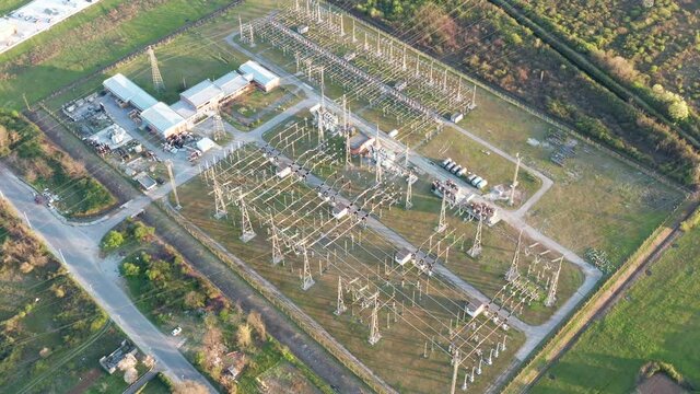 Electrical substation: transformers and grid of pylons, lines and wires. Long-range energy transmission and high voltage electric power distribution system. Aerial drone view.