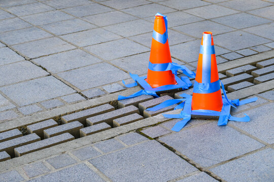 Stone Patio With Orange Safety Cones And Blue Painters Tape Blocking Off Loose Bricks
