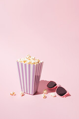 Pop corn striped box and glases for a movie night. Retro scene in pastel colors.