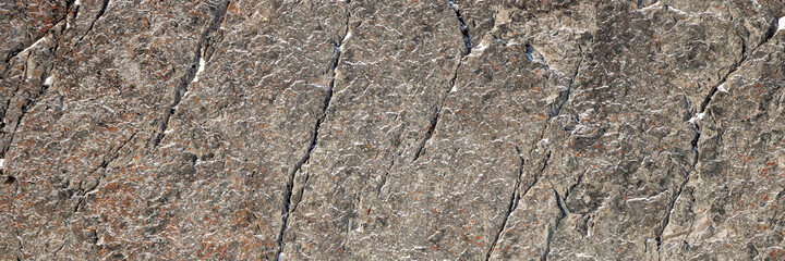 Rock texture. Snow and cracks on the surface of the cliff. Natural stone background.