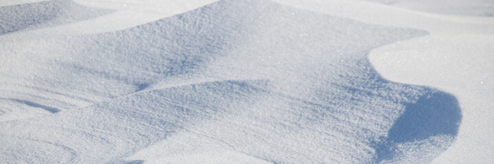 Beautiful winter background with snowy ground. Natural snow texture. Wind sculpted patterns on snow surface. Arctic, Polar region.