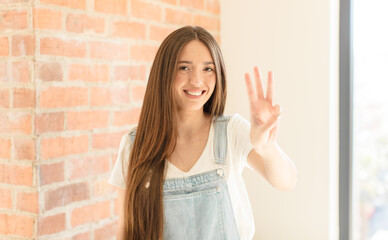 pretty woman smiling and looking friendly, showing number three or third with hand forward,...