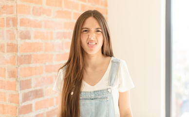 pretty woman feeling disgusted and irritated, sticking tongue out, disliking something nasty and...