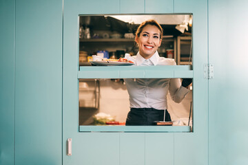 Beautiful young female cook working in restaurant.