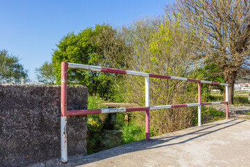 Red and white steel railing abstract pattern of the bridge railing. Metal construction, steel railing on the  bridge against agricultural field in Esposende, Portugal.