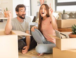 young couple feeling like a happy and excited genius after realizing an idea, cheerfully raising...