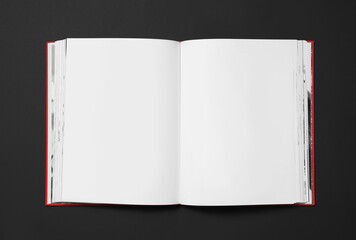 Open book with blank pages on black background, top view. Space for text