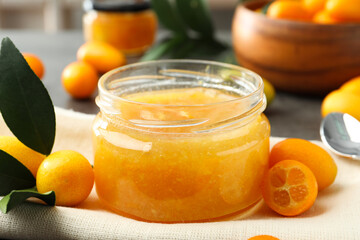 Delicious kumquat jam and fresh fruits on table, closeup