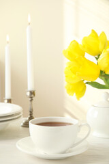 Tea set, candles and flowers on white wooden table