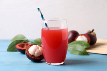Delicious fresh mangosteen juice in glass on light blue wooden table
