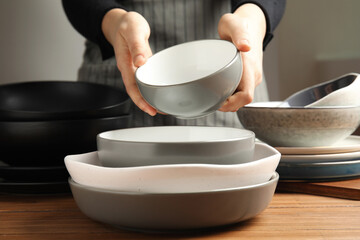 Woman holding bowl over clean dishware, closeup
