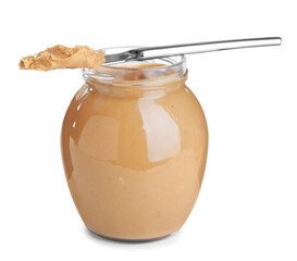 Glass jar and knife with tasty peanut butter on white background