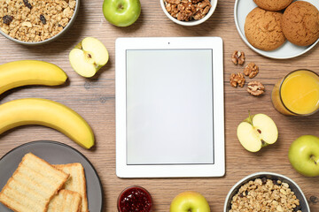 Flat lay composition with tablet and different products on wooden table, space for text