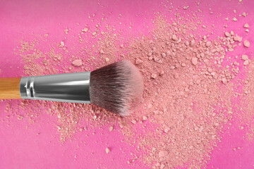 Makeup brush and scattered blush on bright pink background, top view