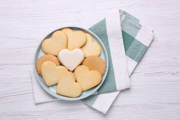 Obraz premium Heart shaped cookies and napkin on white wooden table, flat lay