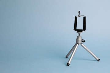 Modern stylish mobile tripod on light blue background. Space for text