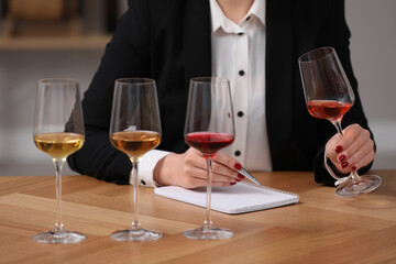 Sommelier tasting different sorts of wine at table indoors, closeup