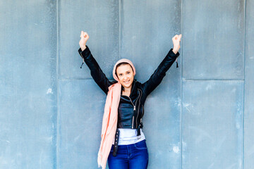 Woman with raised arms with pink headscarf concept beating cancer