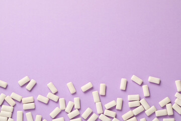 Many chewing gum pieces on violet background, flat lay. Space for text