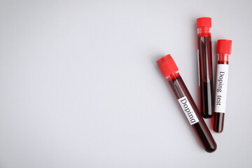 Test tubes with blood samples on light grey background, flat lay and space for text. Doping control