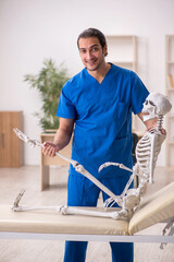 Young male doctor and skeleton patient in the clinic