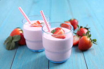 Delicious drink with strawberries on light blue wooden table