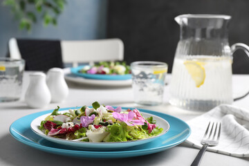 Fresh spring salad with flowers served on white table