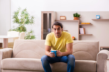 Young man student drinking coffee at home